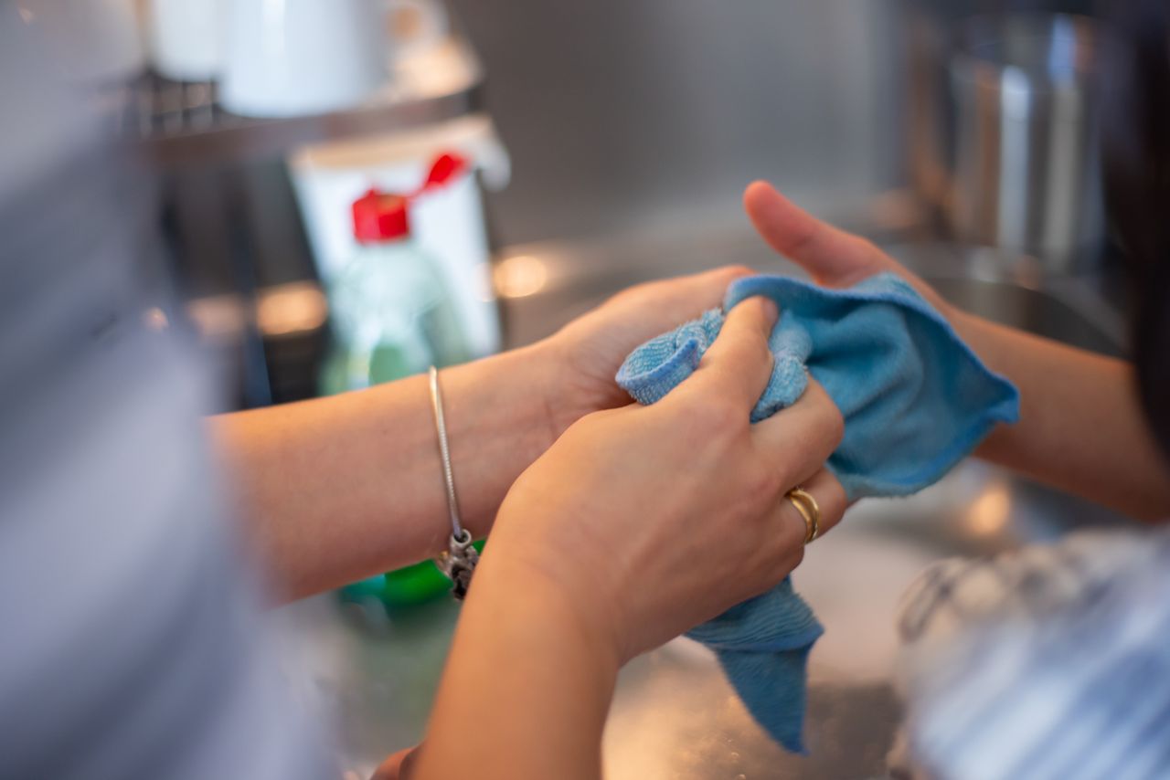 gallery-6 Detailed image of two people cleaning using a blue cloth indoors. Perfect for hygiene concepts.