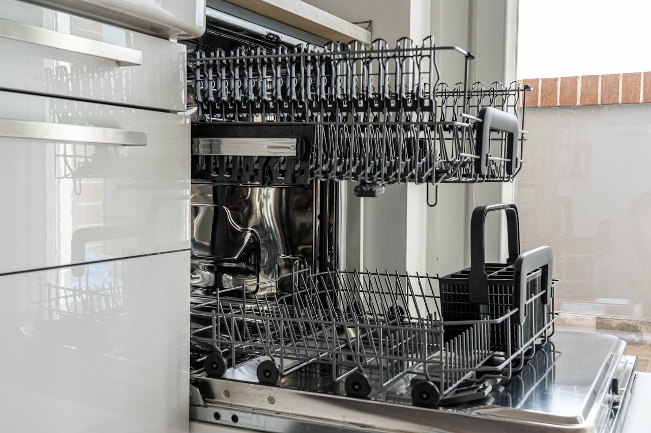 about-01 Open and empty dishwasher in a sunlit modern kitchen ready for use.